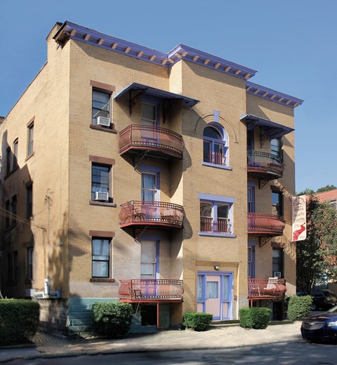 A tan building with a blue door and a balcony.
