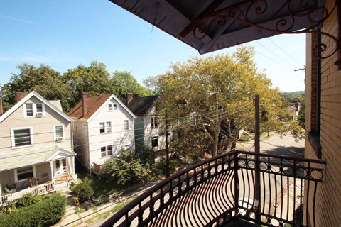 A balcony with a metal railing overlooks a residential street.