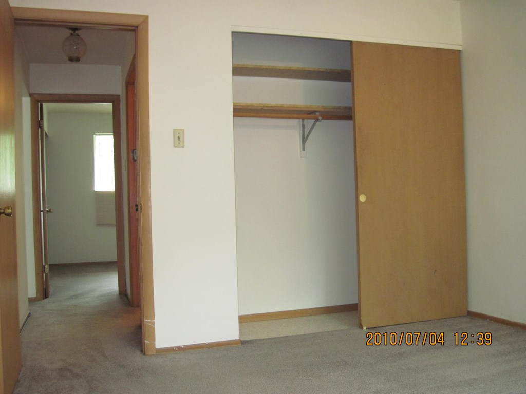 a bedroom with an open closet and a hallway with a door open