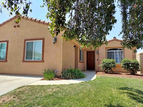 A house with a brown exterior and a green lawn in front.