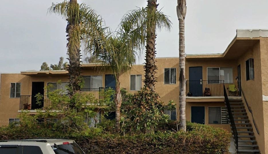 an apartment building with palm trees in front of it