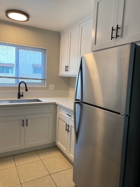 A kitchen with a stainless steel refrigerator and white cabinets.