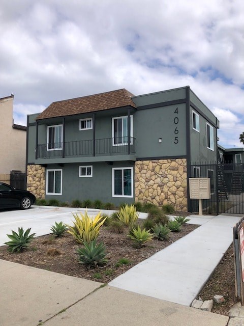 A house with a grey facade and a stone wall.