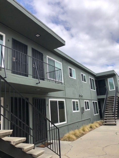 A grey building with black railings and steps leading to the entrance.