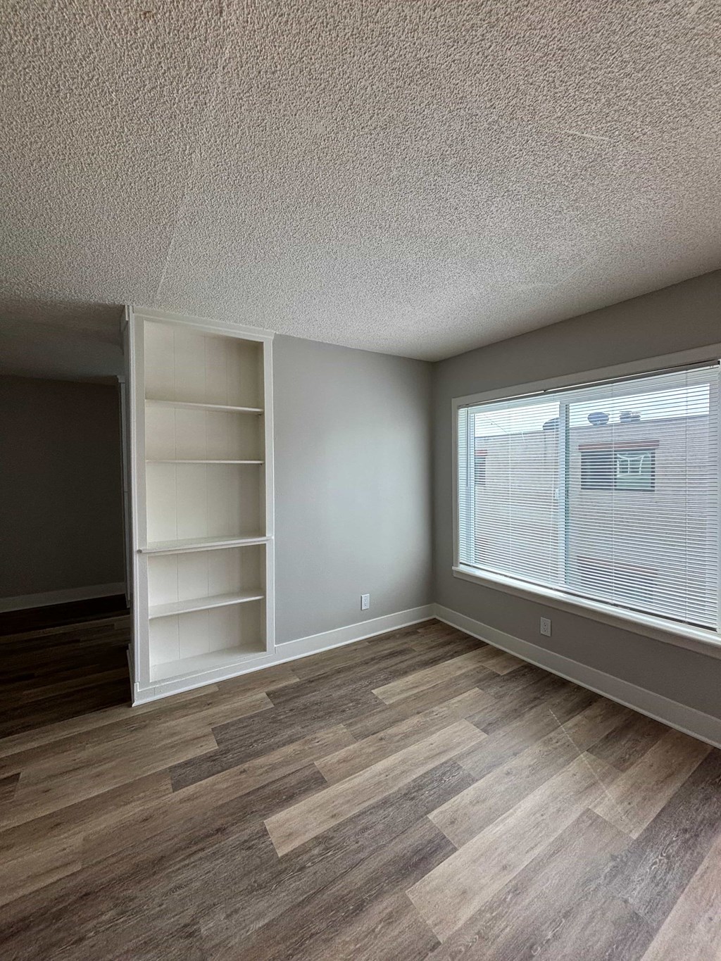 A room with a large window and a built-in shelf unit.
