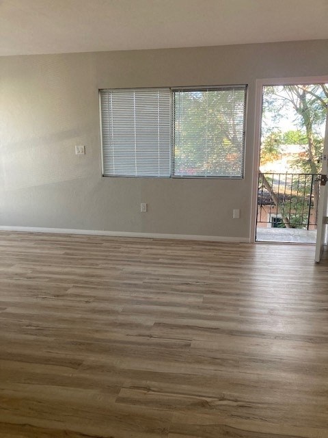 an empty living room with wood floors and a window