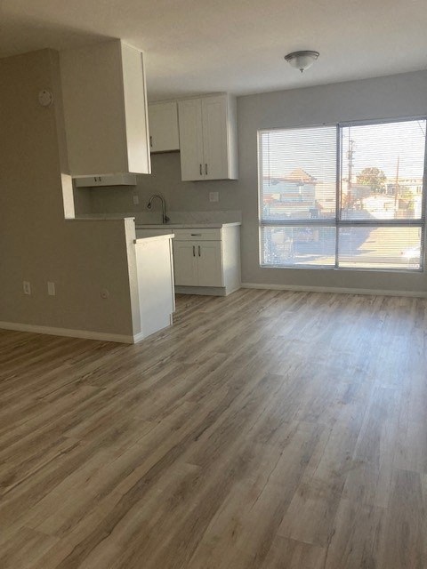 an empty kitchen with wooden floors and white cabinets