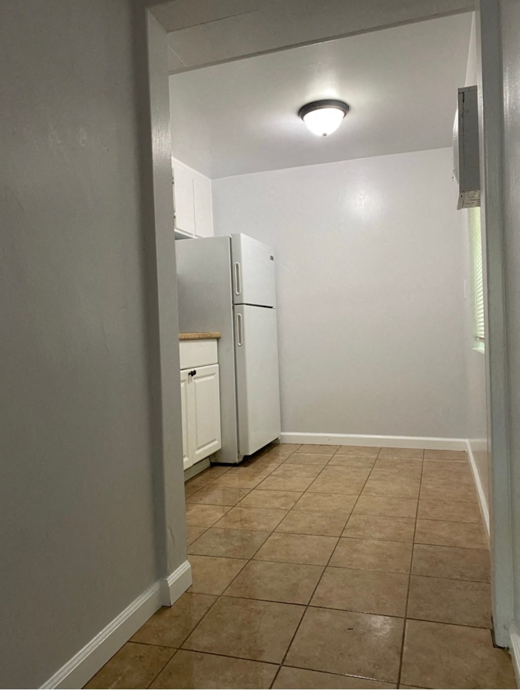 an empty kitchen with a refrigerator and a window