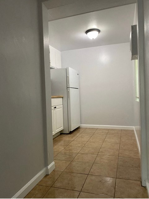 an empty kitchen with a refrigerator and a window