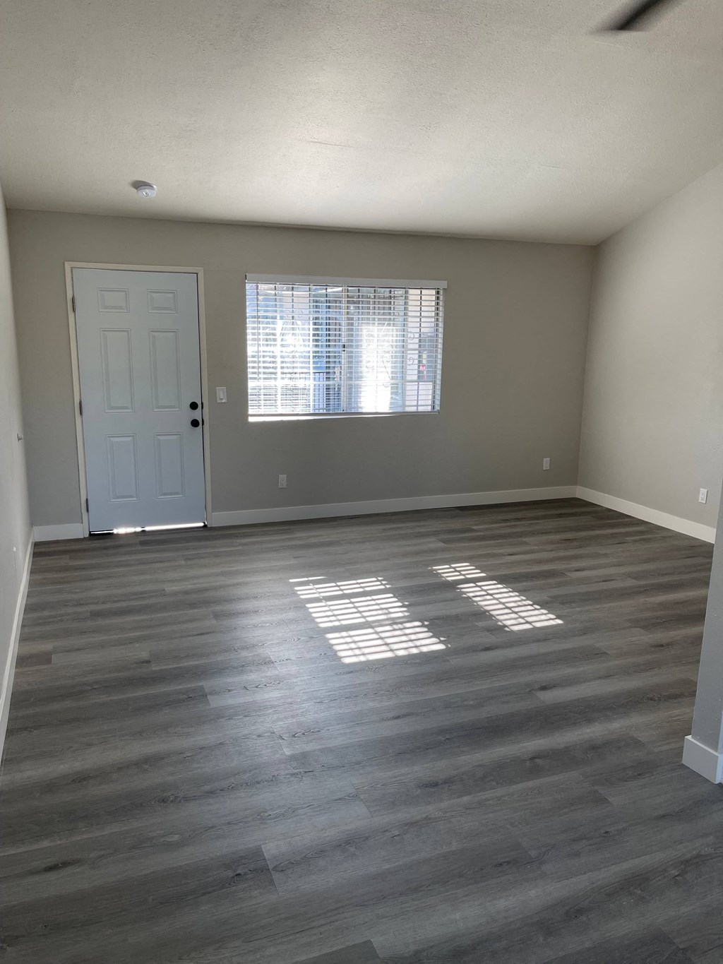 an empty living room with wooden floors and a white door