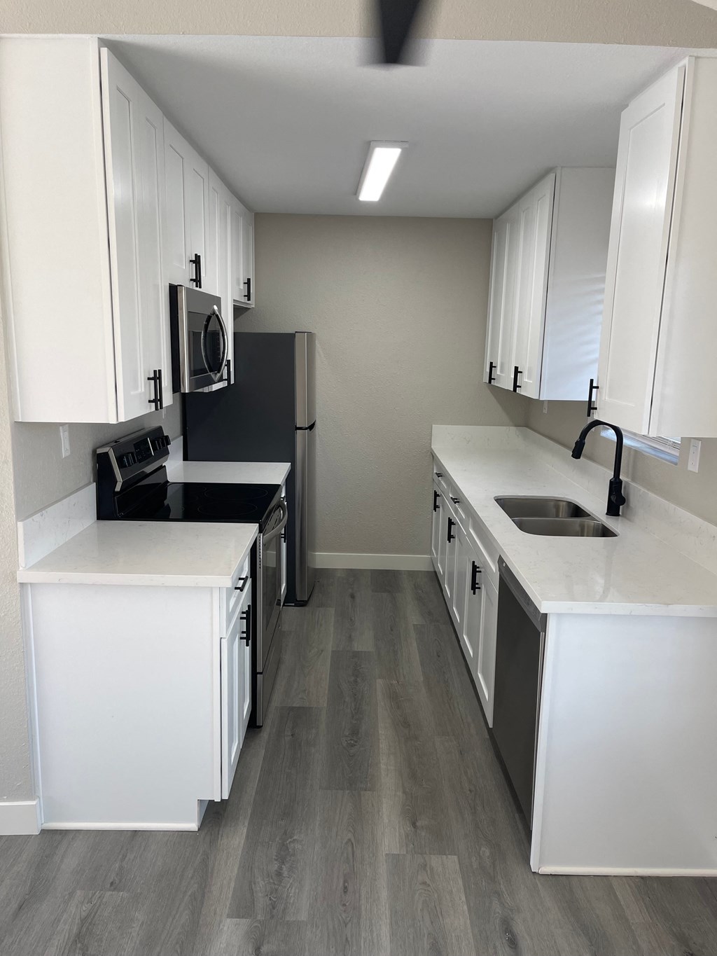 a kitchen with white cabinets and a sink and a refrigerator