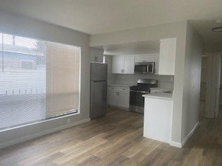 an empty kitchen with a large window and a refrigerator