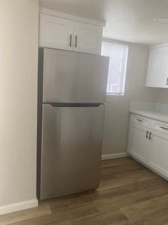 a stainless steel refrigerator in a kitchen with white cabinets