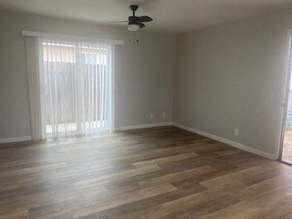an empty living room with wood floors and a ceiling fan