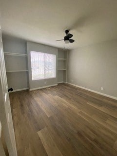 an empty living room with wood floors and a ceiling fan
