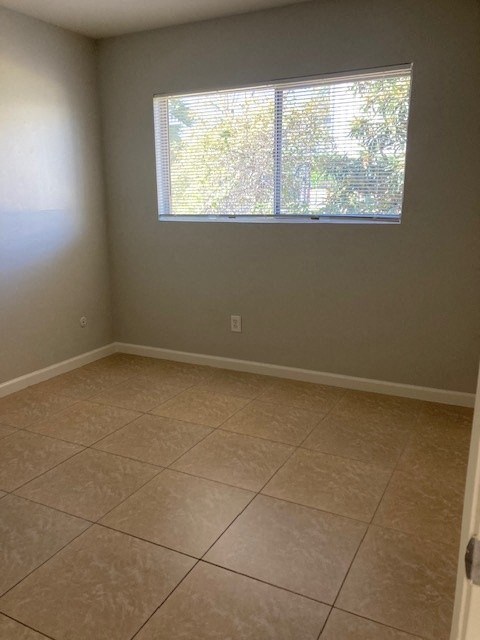 an empty room with a window and tiled floors