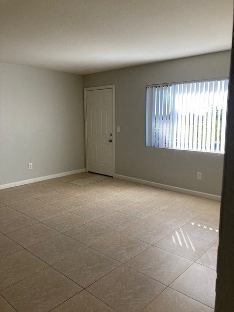 an empty living room with a door and a window