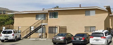 A beige house with a black gate and a car parked in front.