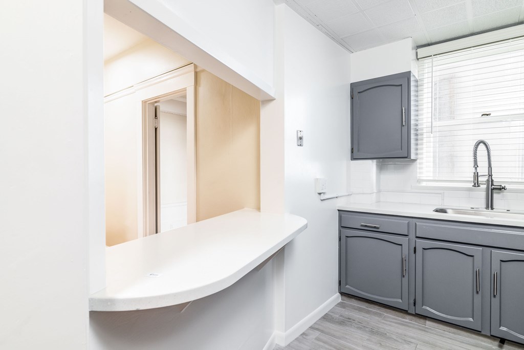A kitchen with a sink, cabinets, and a window.