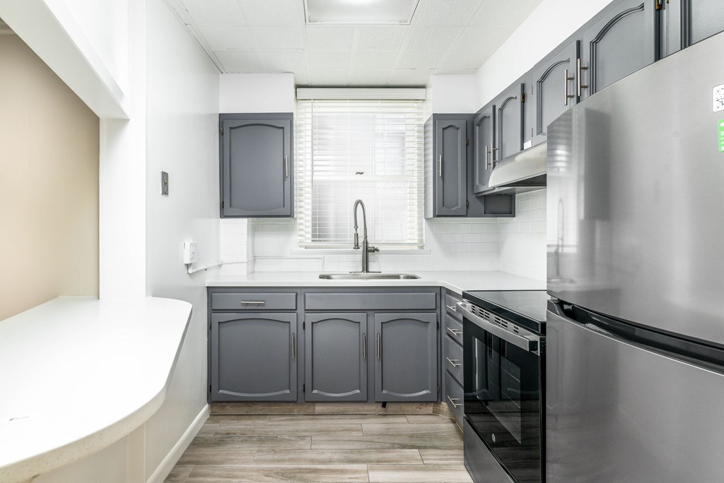 A modern kitchen with a stainless steel refrigerator and dark grey cabinets.