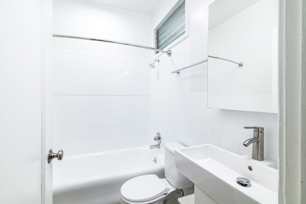 A white bathroom with a toilet, sink, and shower.