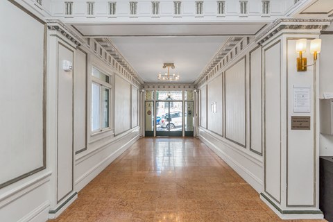A long hallway with white walls and a brown floor.