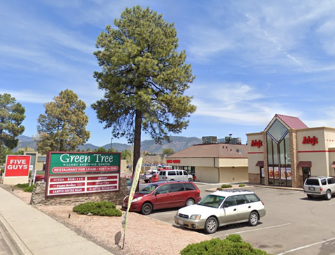 A parking lot with a sign for Green Tree and a building with a red roof.
