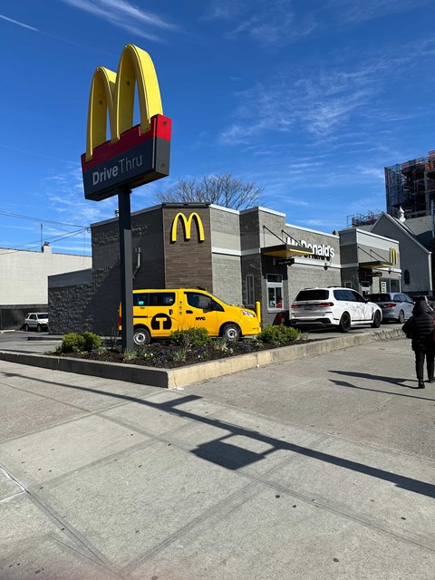A McDonald's drive thru with a yellow car in front.