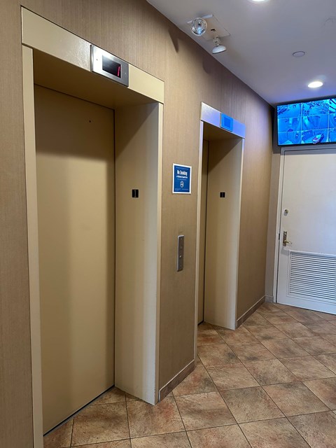 Two elevators with a blue sign on the right one.