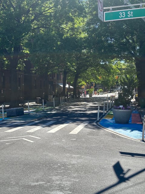 A street view of 33rd street with trees and a crosswalk.