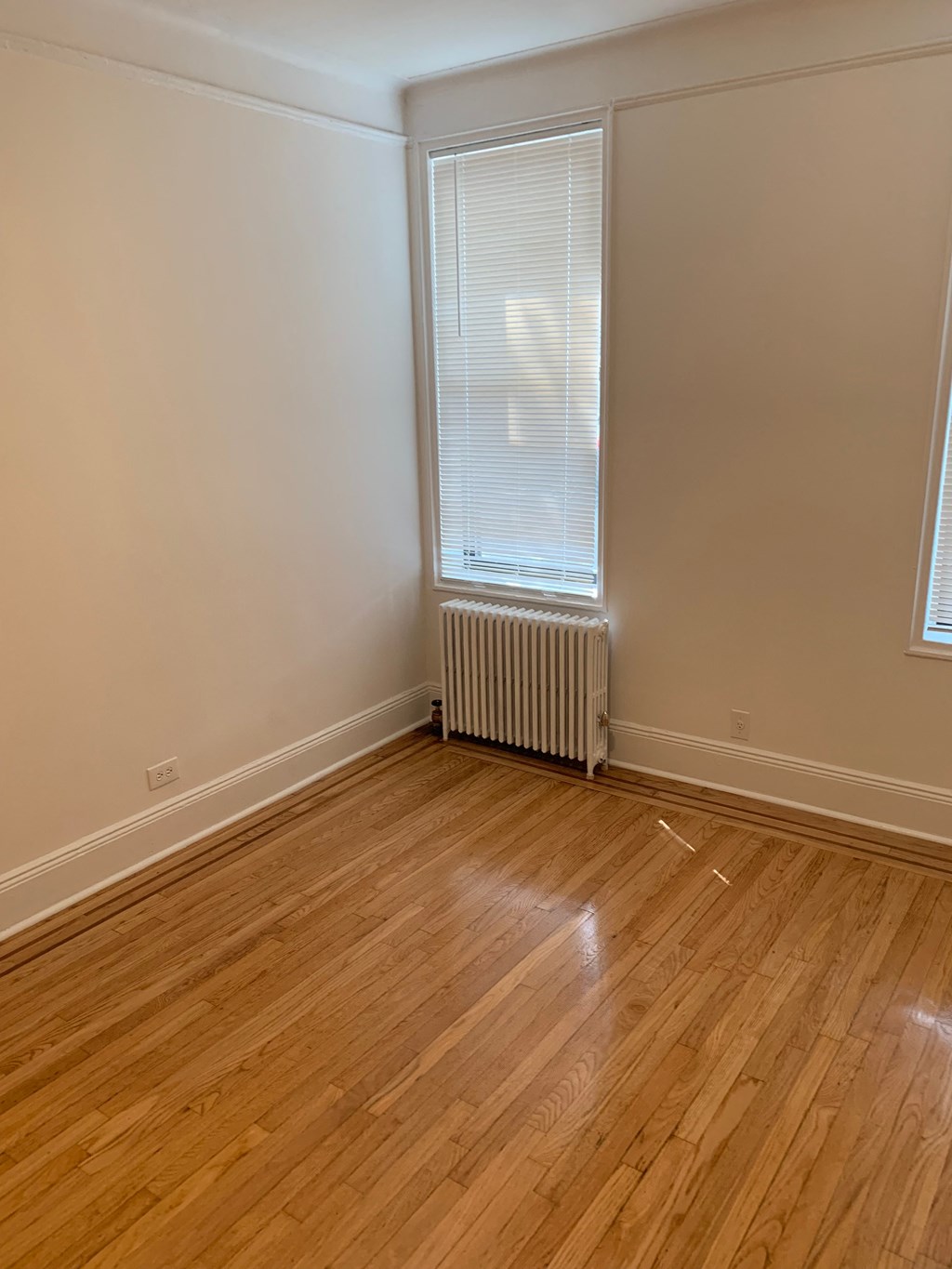 a living room with wood floors and a radiator and a window