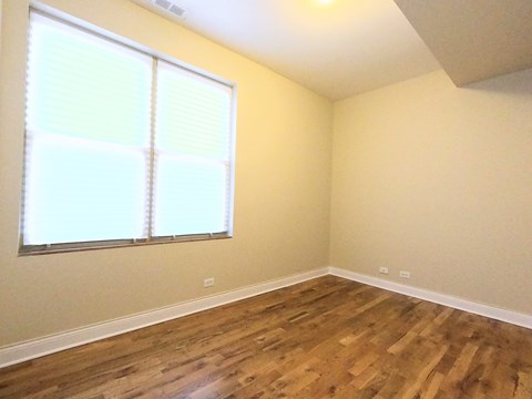 A room with wooden floors and a window with blinds.