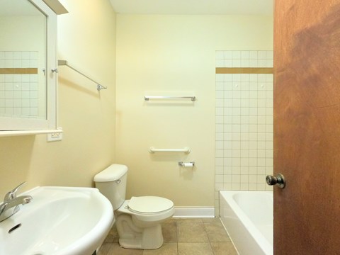 A white toilet sits in a bathroom next to a sink and a bathtub.