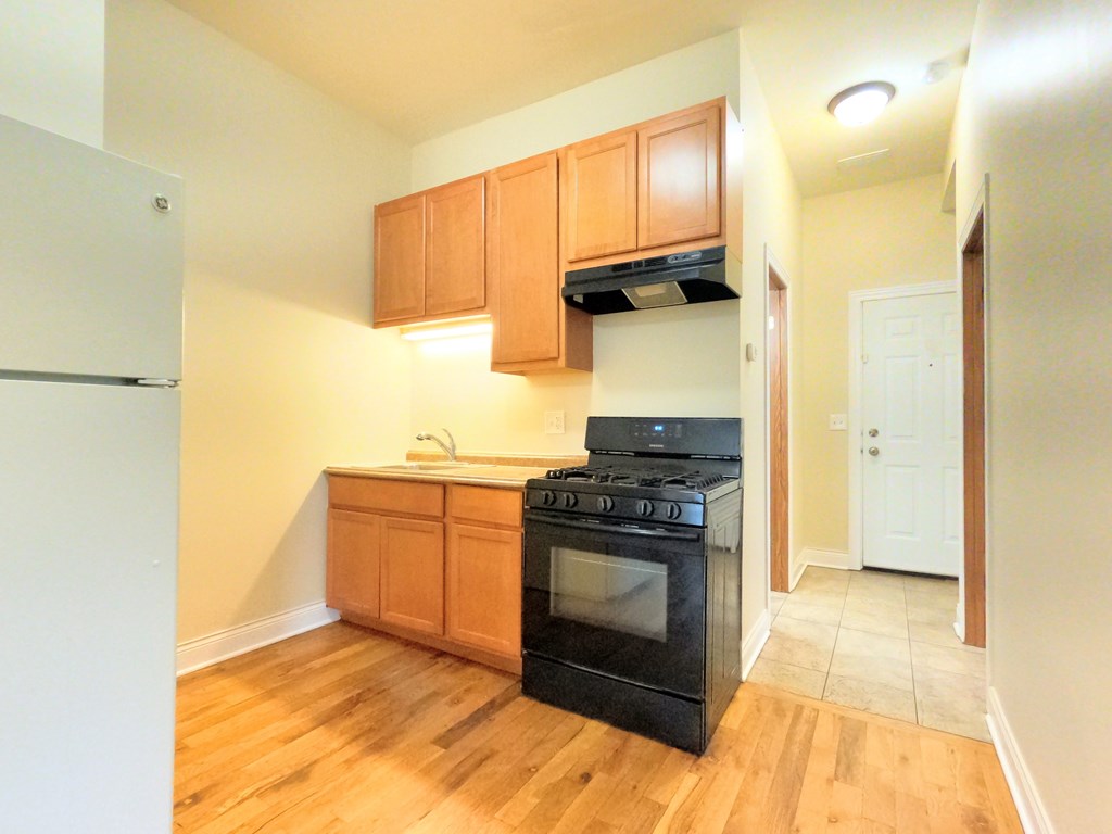 A kitchen with a black oven and wooden cabinets.