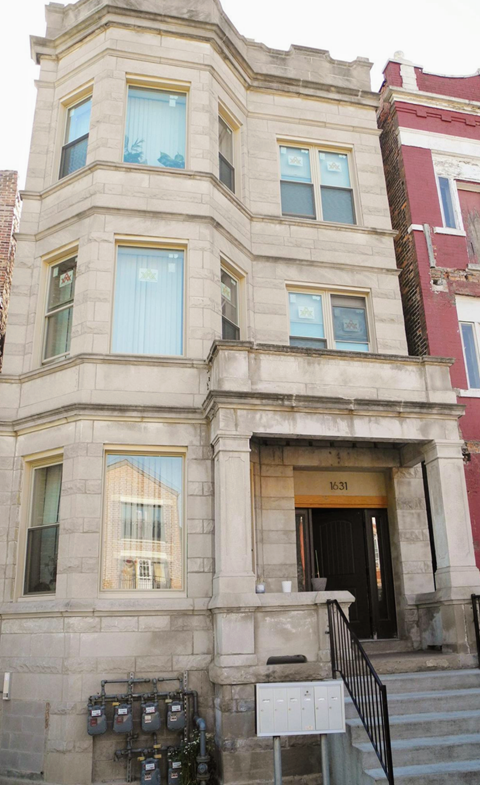 A building with a black door and windows with white curtains.