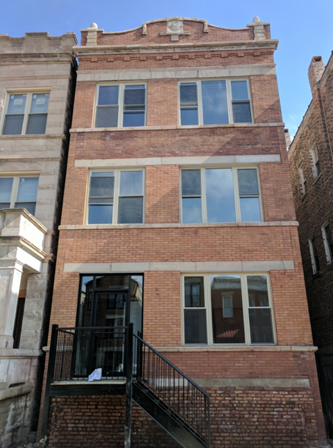 A brick building with a balcony and a window with a reflection of a person.