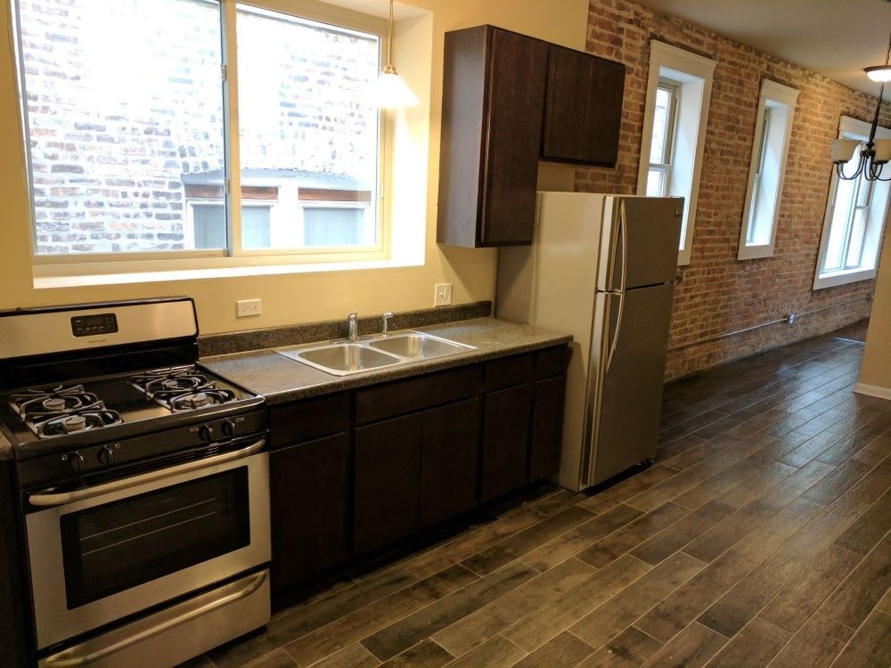 A kitchen with a stove, sink, and refrigerator.