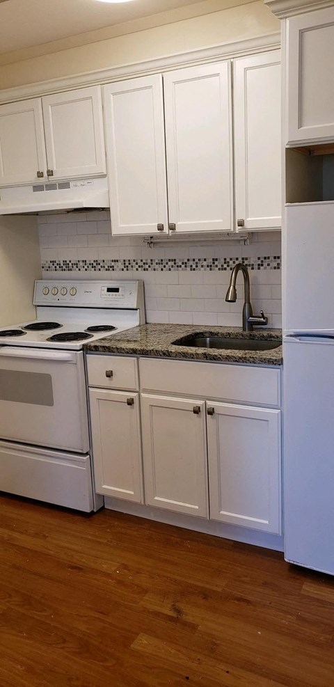 a white kitchen with white cabinets and a sink