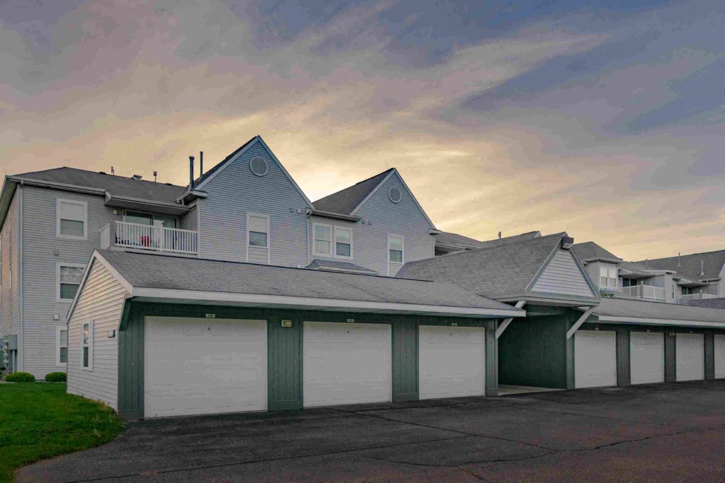 a white house with green garage doors and a cloudy sky