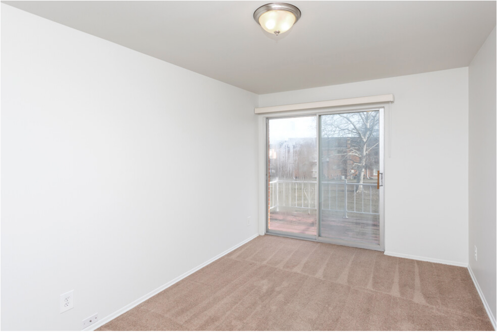an empty living room with a sliding glass door to a balcony
