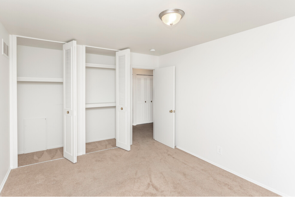 a bedroom with white closets and a carpeted floor