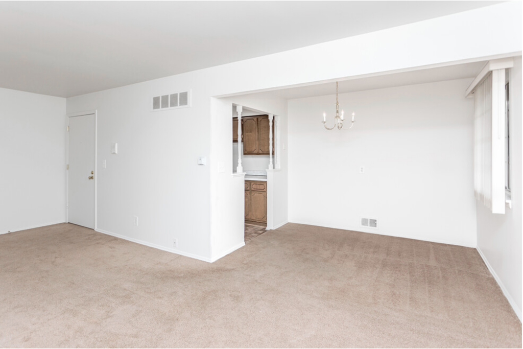 an empty living room with white walls and carpet