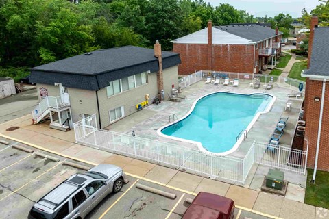 A swimming pool is surrounded by a fence in a parking lot.