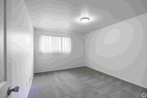 A room with a door, a window with blinds, and a ceiling light.