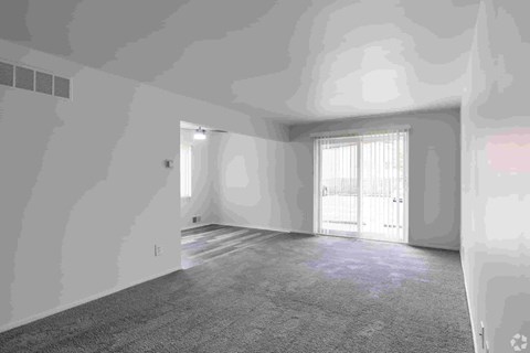 A room with a carpeted floor and a window with blinds.