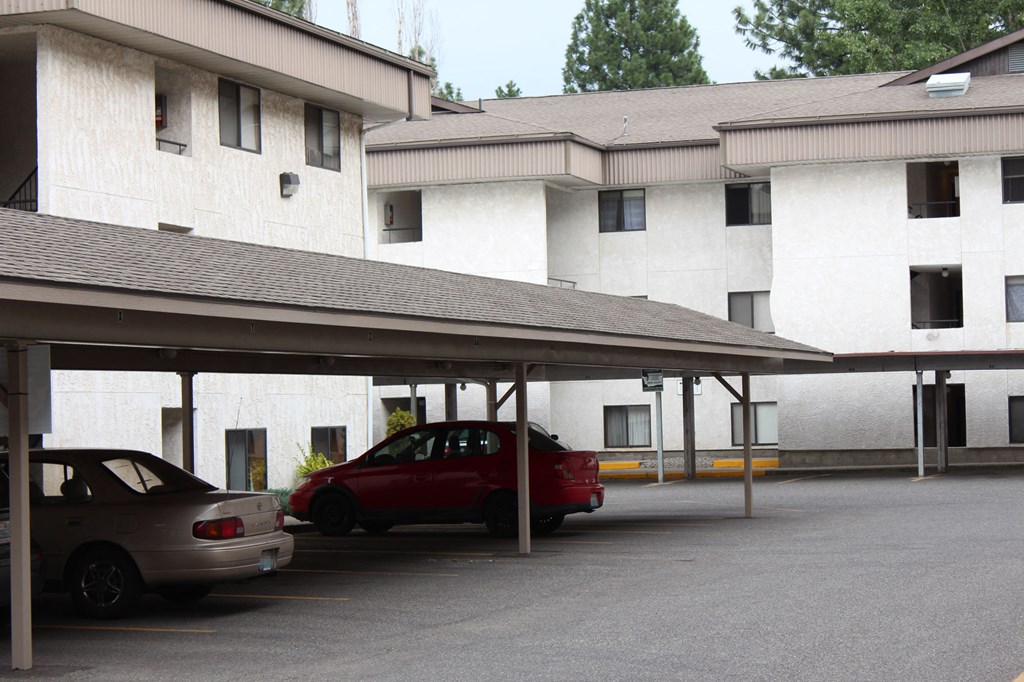 a parking lot in front of a white building with cars parked in it