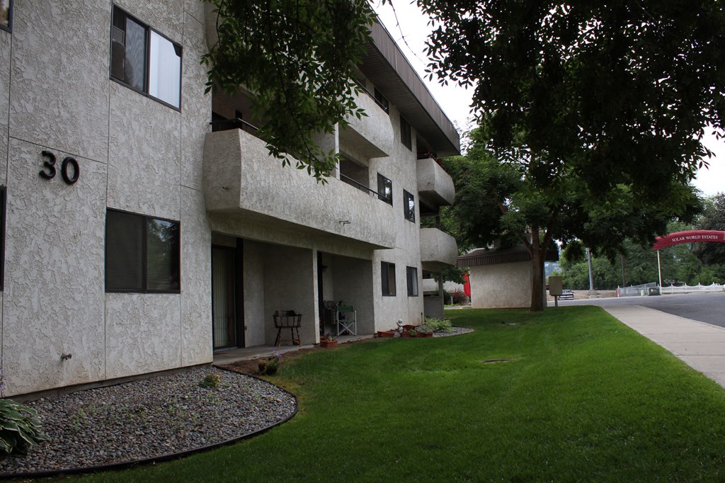 a view of the side of a building with grass and trees