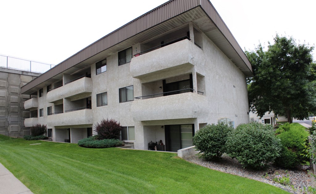 a large white building with a lawn and bushes in front