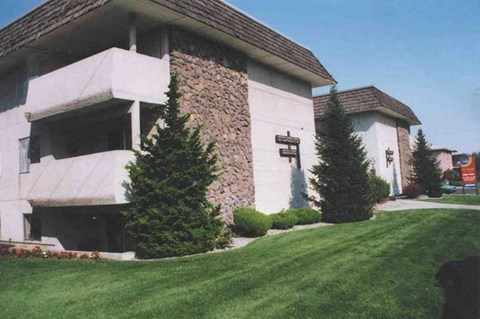 a white building with two pine trees in front of it