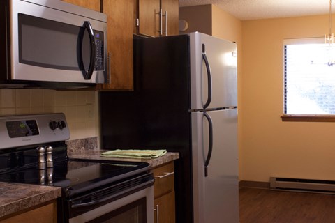 A kitchen with a black refrigerator and a black stove top oven.